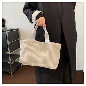 Detailed view of the off-white corduroy texture and sturdy handles of this tote bag