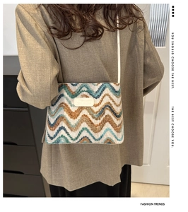 Detail view of woven wool bucket bag with blue and brown chevron pattern and leather patch