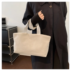 Close-up of beige corduroy tote bag showing ribbed texture and wide shoulder straps