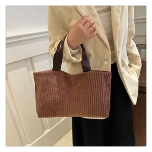 Detailed texture of brown corduroy bucket bag with reinforced woven handles for daily use