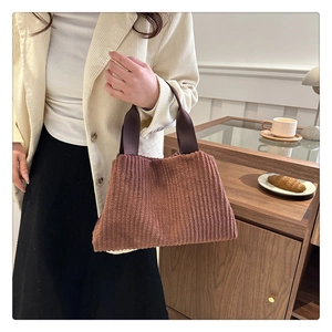 Close-up of brown corduroy tote bag featuring vertical stripes and durable fabric handles