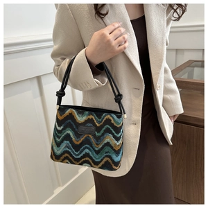 Detail of chevron fabric pattern and black leather logo on stylish bucket handbag