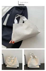 Macro view showing the white corduroy fabric texture and sturdy woven handle of the tote bag