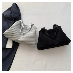Close-up of ribbed knit tote bags in grey and black with satin handles on white fabric