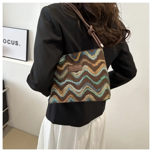 Detail of bohemian woven tote bag showing wave patterns and leather shoulder strap