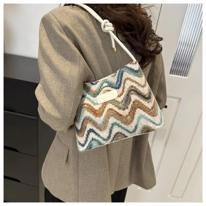 Detail of colorful wavy textured woven wool bucket bag with chic white leather knotted strap