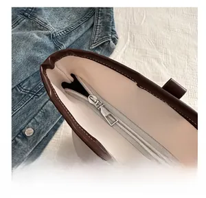 Close-up of smooth metal zipper and brown leather trim on minimalist bucket tote bag