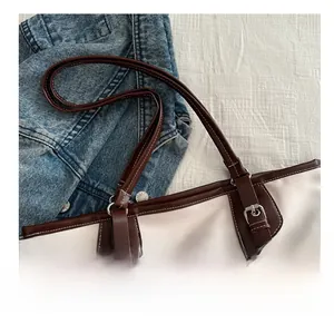 Close-up of contrast bucket bag handle and silver buckle on cream and brown leather