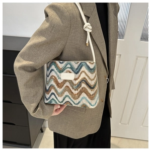Detail of tweed bucket bag showing woven wave pattern and white leather logo patch