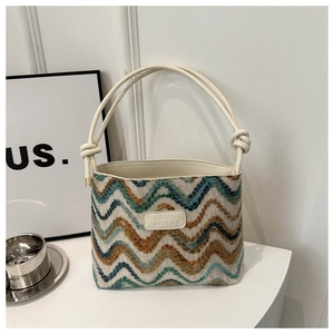Detail of wavy knit texture and leather brand label on a colorful striped bucket bag