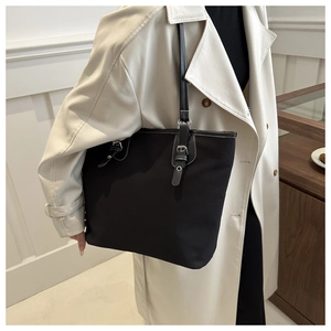 Close-up of black canvas tote bag showing high-capacity design and silver buckle detail