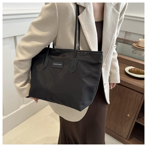 Close-up of black nylon tote bag with Fashion & Bags logo patch and slim shoulder straps