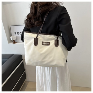 Detailed view of white nylon tote bag with brown leather handles and brand logo tag