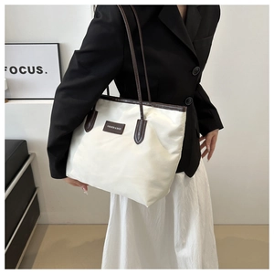 Detailed view of large white nylon tote bag with brown straps worn on a shoulder