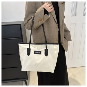 Close-up of beige nylon tote bag with black leather straps and fashion textile label