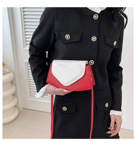 Détail d'un sac bandoulière cœur rouge et blanc porté avec un blazer vintage noir