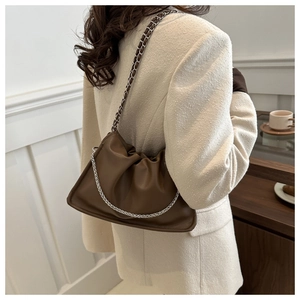 Model wearing a dark brown pleated dumpling bag with silver chunky chain strap and detail