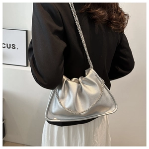 Détail du sac seau en similicuir argenté avec fine bandoulière chaîne porté par un mannequin