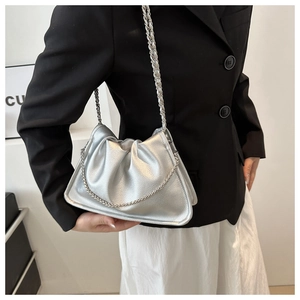 Sac seau plissé argenté avec bandoulière chaîne porté par un mannequin chic