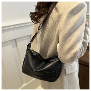 Detail of soft black PU leather shoulder bag with wide adjustable strap and gold hardware