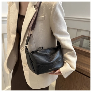 Detail of black soft PU leather bag featuring a wide jacquard woven shoulder strap