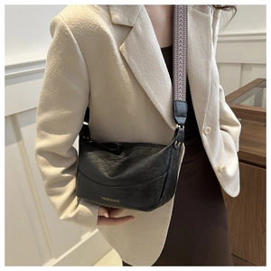 Detail of black faux leather half-moon crossbody bag with geometric jacquard strap