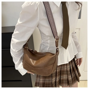 Brown vintage faux leather shoulder bag with wide geometric pattern strap on model