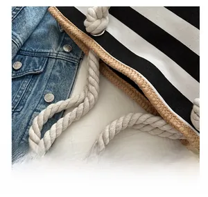 Detail of black and white striped tote bag with rope handle and woven trim on denim jacket