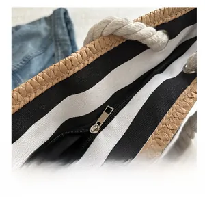 Detail of straw tote bag showing black and white striped lining and metal zipper closure
