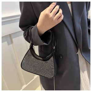 Detail of a black hobo bag with sparkling rhinestones held by a model in a suit