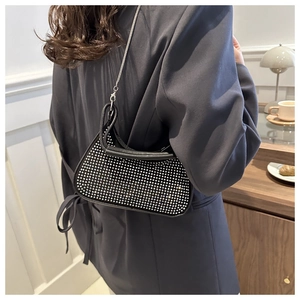 Detail of a black crossbody bag with silver rhinestones and a metal chain strap