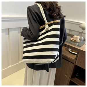 Detail of nautical black and white striped canvas tote bag with thick woven rope handles