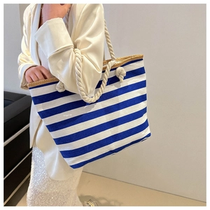 Blue and white striped canvas tote bag detail featuring rope handles and straw trim