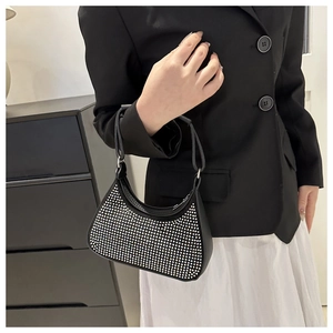 Detail shot of a black crescent shoulder bag with silver rhinestones on a female model