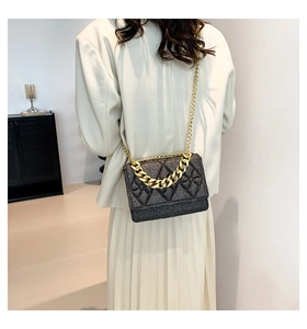 Detail of black shimmer quilted crossbody bag with golden chain and elegant texture