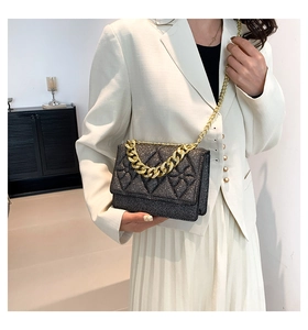 Close-up of black glitter crossbody bag with gold chain and diamond quilted texture
