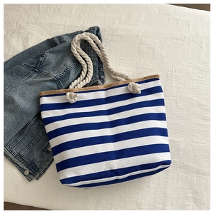 Detail of blue and white striped canvas tote bag with white rope handle on denim jacket