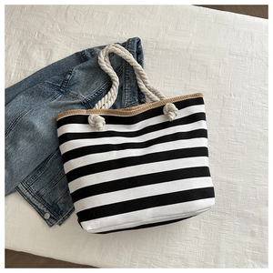Detail of canvas tote with black stripes, straw trim, and thick cotton rope handles