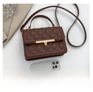Brown quilted crossbody bag size comparison with a smartphone on white background
