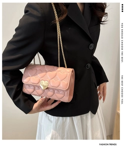 Détail du sac bandoulière matelassé rose avec fermoir cœur porté par un mannequin chic