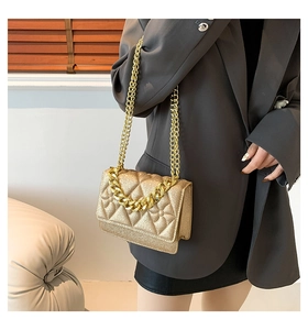 Detailed close-up of quilted gold glitter crossbody bag with elegant metal chain strap