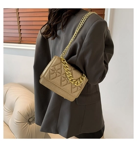 Close-up of golden quilted cross-body bag with chunky metallic chain strap detail