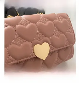Détail du sac matelassé rose avec fermoir en cœur doré et bandoulière en chaîne dorée