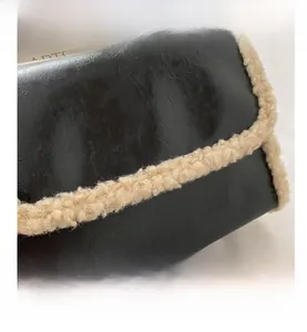 Detail of black leather hobo bag featuring beige faux fur trim and interior brand label