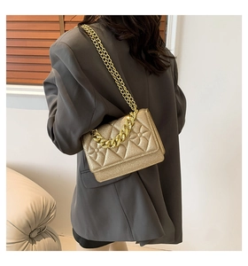 Detailed view of gold glitter crossbody bag with quilted pattern and chunky metal chain