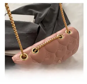 Détail du sac bandoulière rose matelassé avec motifs cœurs et œillets en métal doré