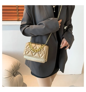 Detail of gold glitter quilted crossbody bag with dual metallic chain straps on model