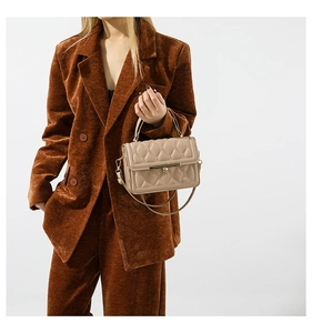 Detailed view of beige faux leather handbag with quilted stitching and metal clasp