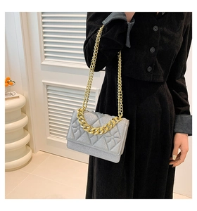 Detail of silver pearl quilted crossbody bag featuring golden chain and shiny finish