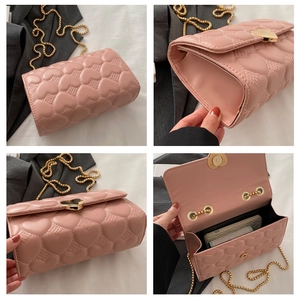 Détail du sac à bandoulière rose matelassé cœur montrant l'intérieur et la chaîne dorée